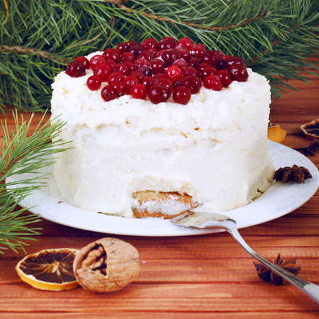 Holiday layered cake with cream and cranberry decoration under christmas tree
