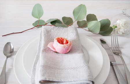 Decorated table setting with linen napkins, white carnation flowers, eucalyptus leaves and silverwareの写真素材