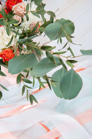 Beautiful bridal bouquet made of white and orange flowers, ribbon and eucalyptus leavesの写真素材