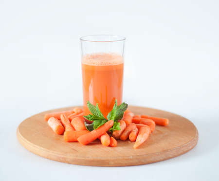 Carrot juice in a glass with small peeled carrots and mint leavesの写真素材