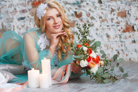 Charming young blond woman with curly hair holding fresh flowers bouquet with roses, carnations and eucalyptus leavesの写真素材