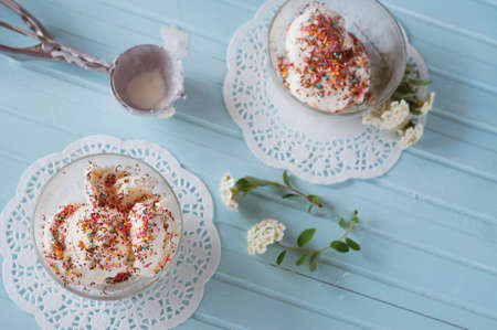 Vanilla ice cream in bowls sprinkled with chocolate and multicolored sprinklesの写真素材