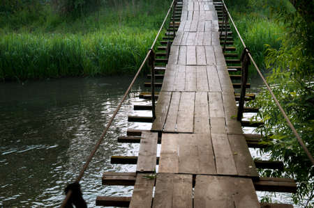 Old suspension bridge in an old mountain village in sunset light in summer
