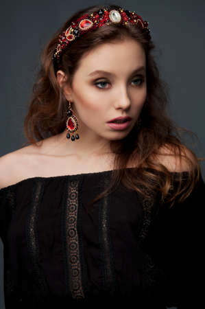 Passionate woman with long wavy hair dressed in black wearing beaded ruby garnet headpiece and earringsの写真素材