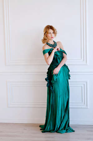 Shapely blond woman in green restoration evening silk gown and beaded necklaceの写真素材