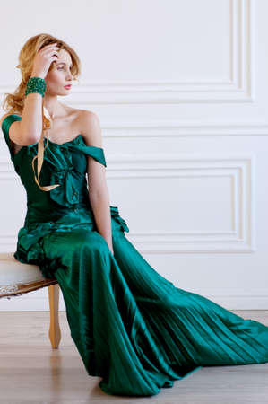 Shapely blond woman in green restoration evening silk gown and beaded braceletの写真素材