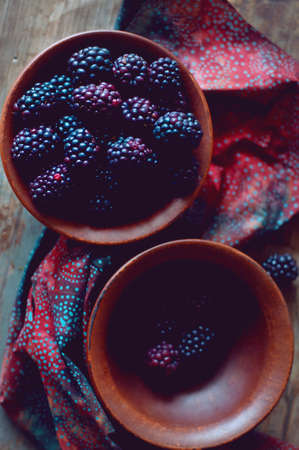 Fresh wild dewberries in a clay bowl on an old  wooden table. Summer berries.