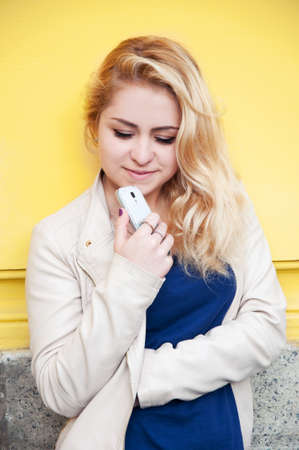 Happy smiling young blond woman thinking happily about phone calling to her boyfriendの写真素材