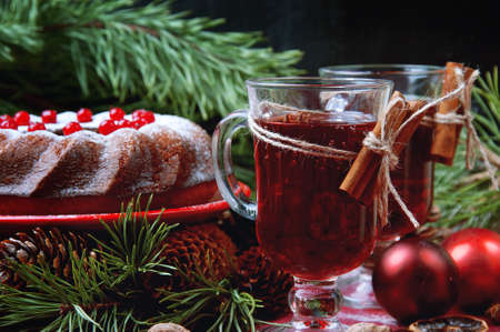 Christmas table setting. Bundt cake pudding sprinkled with sugar powder decorated with red currant and mulled wine.の写真素材