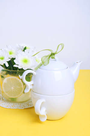 Yellow summer table setting with white plates and chrysanthemum flowers in a glass vaseの写真素材