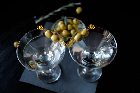 Margarita cocktail alcohol drink in glass with green olives on black backdropの写真素材