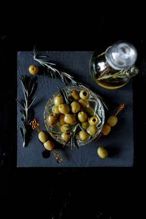 Green olives on picks with rosemary and olive oil in a bottle with herbsの写真素材