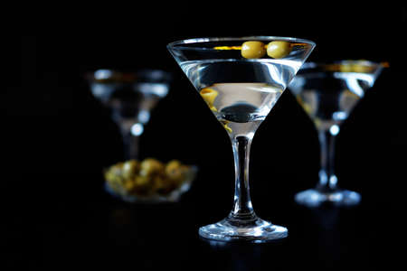 Margarita cocktail alcohol drink in glass with green olives on black backdropの写真素材
