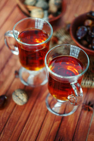 Bowl of dried dates and other spices on old wooden table with tea in glasses.の写真素材
