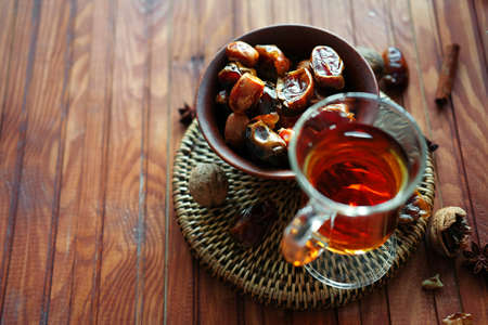 Bowl of dried dates and other spices on old wooden table with tea in glasses.の写真素材
