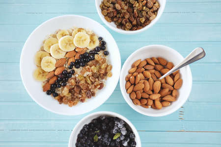 Healthy breakfast. Oatmeal in a white bowl with banana, almond nuts, blueberries and raisins.の写真素材