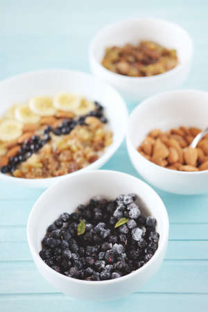 Healthy breakfast. Oatmeal in a white bowl with banana, almond nuts, blueberries and raisins.の写真素材