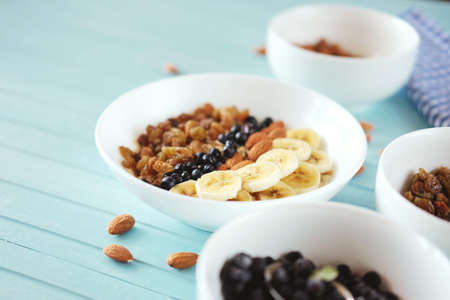 Healthy breakfast. Oatmeal in a white bowl with banana, almond nuts, blueberries and raisins.の写真素材