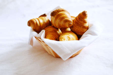Croissants in woven bos with white napkin on linen bedding. Tasty food concept.の写真素材