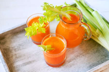 Fresh carrot juice poured into glasses and green celery. Healthy vegetarian food concept.の写真素材