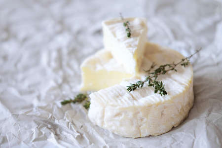 Block of brie cheese on wrapping paper with thyme herbsの写真素材