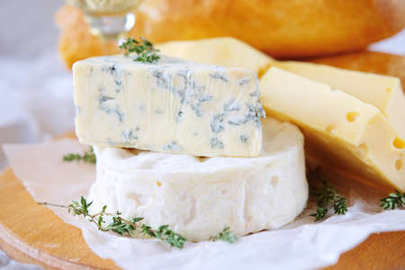 Cheese plate with different kinds of cheese with a glass of white wine and baguetteの写真素材
