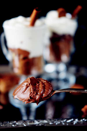 Sweet dessert with chocolate crumbles, cocoa, nuts, whipped cream and cinnamon on silver trayの写真素材