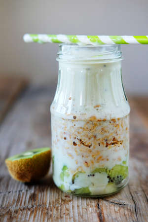 Smoothie bottles with granola, kiwi, nuts, yoghurt and mint. Healthy vegetarian breakfast concept.の写真素材