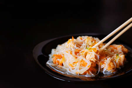 Asian traditional food. Fried rice noodles with chicken meat, vegetable slices sprinkled with sesame seeds.の写真素材