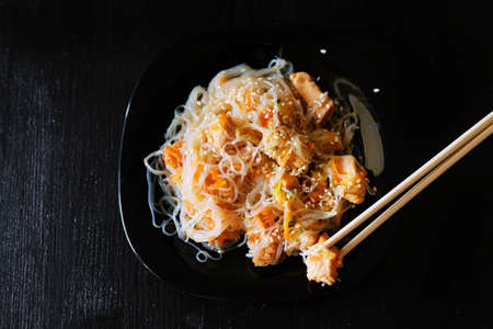Asian traditional food. Fried rice noodles with chicken meat, vegetable slices sprinkled with sesame seeds.の写真素材