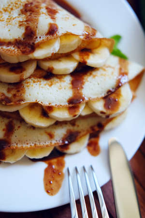 Crepes with chocolate sauce, mint leaves and banana slices. Sweet tasty dessert.