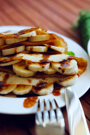 Crepes with chocolate sauce, mint leaves and banana slices. Sweet tasty dessert.の写真素材