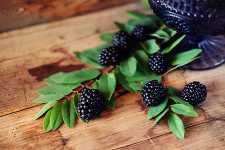 Blackberries on wooden backdrop in dark purple glass bowlの写真素材