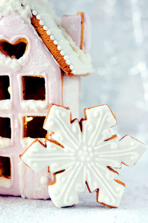 Magical winter christmas picture. Gingerbread house with pink icing with light shining in the windows under snow falling.の写真素材