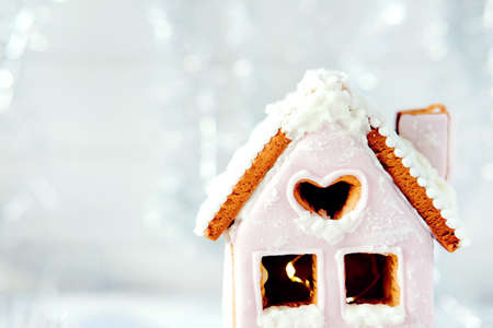 Magical winter christmas picture. Gingerbread house with pink icing with light shining in the windows.の写真素材