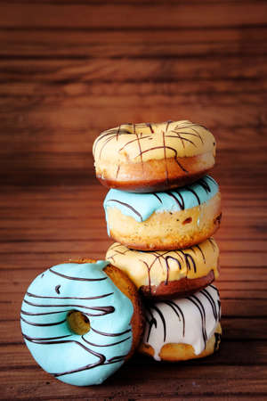Fresh sweet doughnuts with multi colored icing and chocolate frosting. Fast food.の写真素材