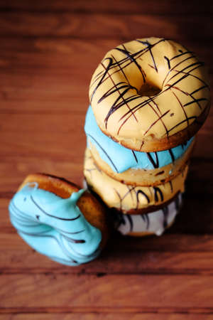 Fresh sweet doughnuts with multi colored icing and chocolate frosting. Fast food.の写真素材