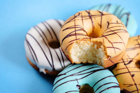 Fresh sweet doughnuts with multi colored icing and chocolate frosting. Fast food.