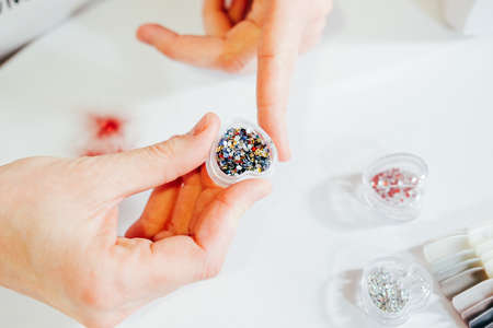 Multicolored rhinestones in a plastic heart shaped box for makeup and manicure decorationの写真素材