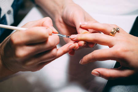 Gel nail extensions build up process. Women at beauty parlour doing manicure.の写真素材