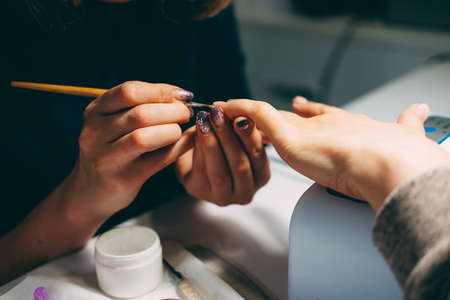 Gel nail extensions build up process. Women at beauty parlour doing manicure.の写真素材