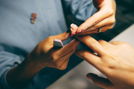 Gel nail extensions build up process. Women at beauty parlour doing manicure.