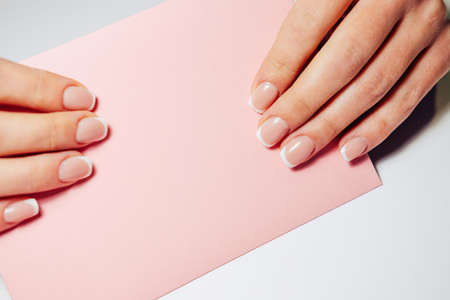 French nail extensions. Women with beautiful manicure and wedding ring holding a pink envelope with weding invitation.の写真素材