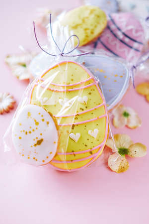 Easter holiday decoration  gift basket.  Egg shaped cookies with frosting on pink backgroundの写真素材