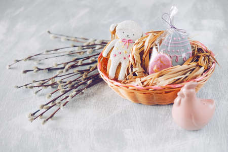 Easter holiday decoration.  Egg shaped cookies with frosting in a woven basket and blooming willow branches の写真素材