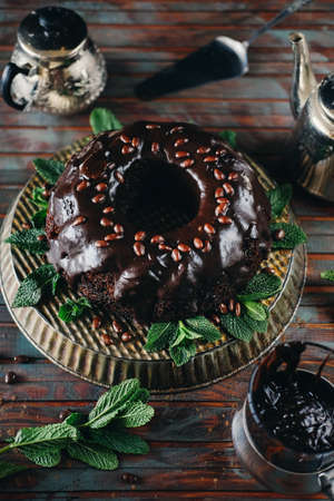 Sweet chocolate cake with cacao icing and decorated with mint and chocolate dropsの写真素材