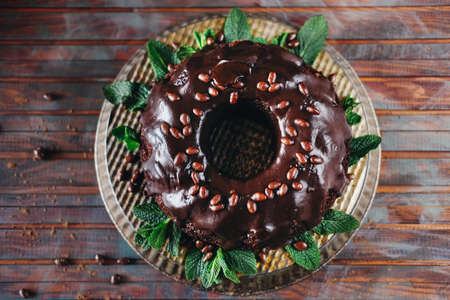 Sweet chocolate cake with cacao icing and decorated with mint and chocolate drops