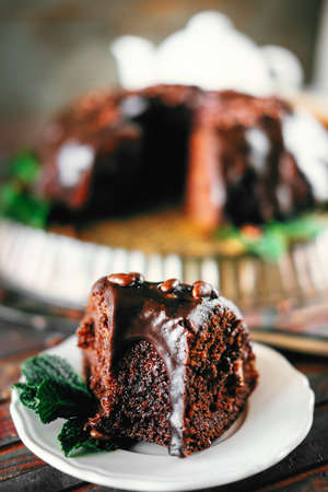 Sweet chocolate cake with cacao icing and decorated with mint and chocolate dropsの写真素材