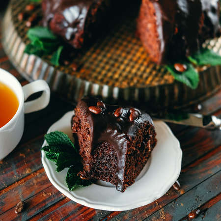 Sweet chocolate cake with cacao icing and decorated with mint and chocolate dropsの写真素材