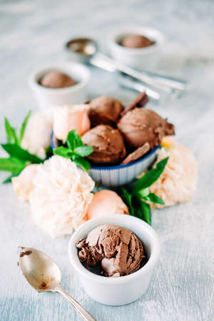 Three scoops of dark chocolate ice cream sundae with sweet floral flavour surrounded by roses, carnations and mint leavesの写真素材